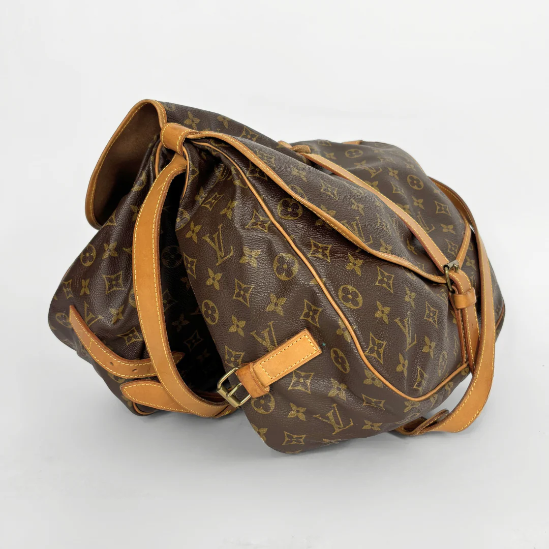 Brown monogram handbag with tan leather strap on a white background