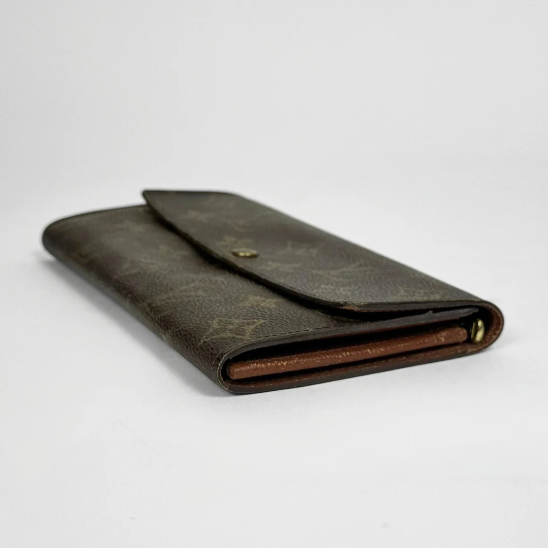 Brown wallet with gold monogram pattern on a white background