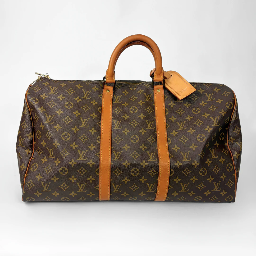 Brown hand bag with orange accents and a prominent logo pattern on a white background