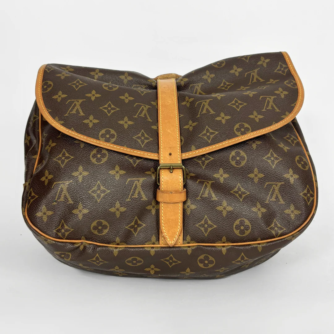 Brown monogrammed bag with tan leather accents on a light gray background
