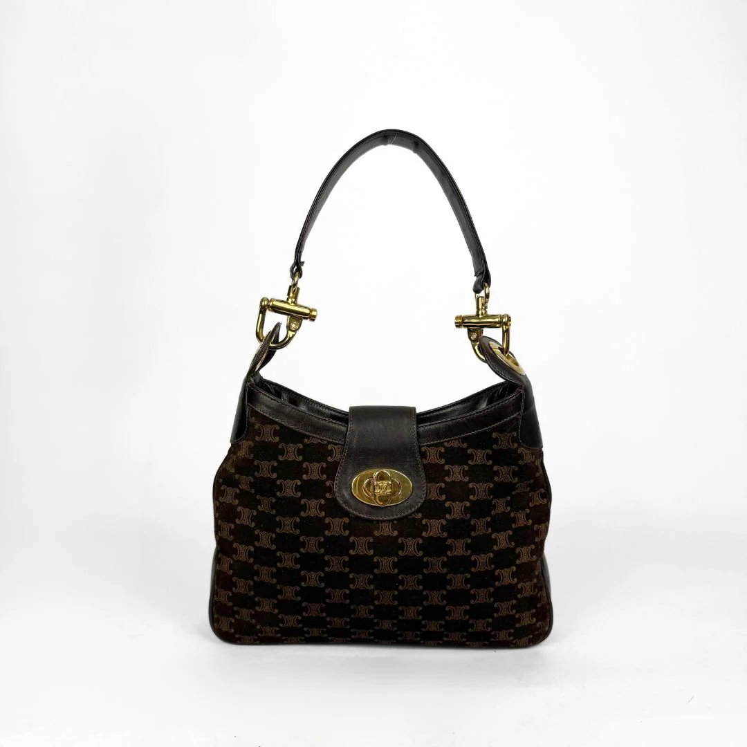 Brown patterned handbag with gold accents on a white background