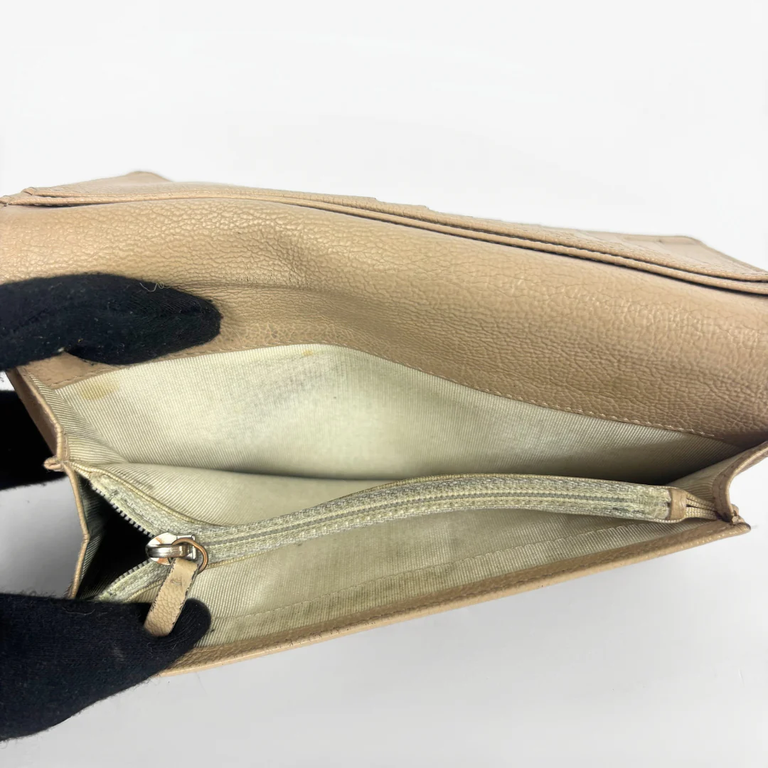 Inside of the wallet (beige) with a gold zipper on a white background