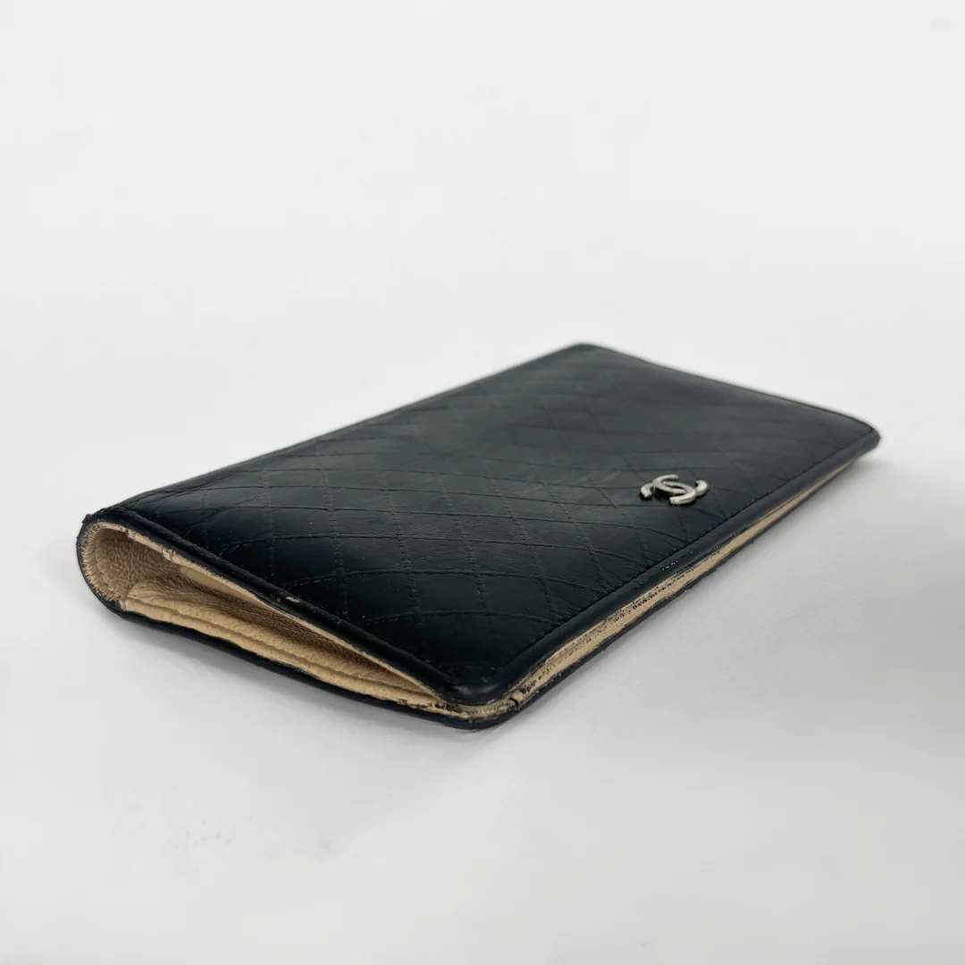 Black quilted wallet with Chanel logo on a white background