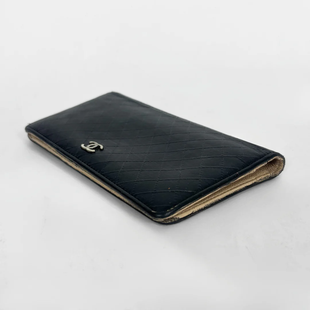 Black quilted wallet with Chanel logo on a white background