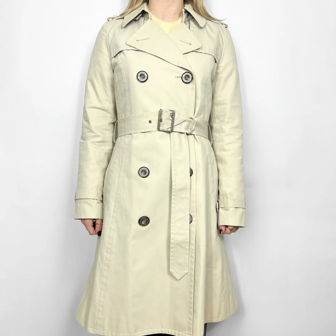 Beige trench coat worn by a person on a white background