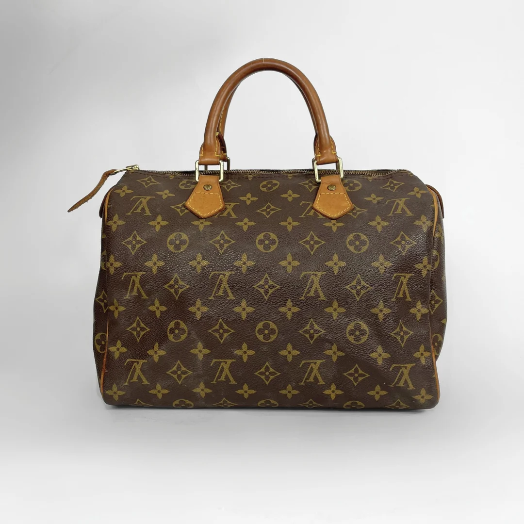 A Louis Vuitton monogram canvas Speedy handbag in dark brown with tan leather handles and gold-tone hardware, photographed against a neutral light gray background.