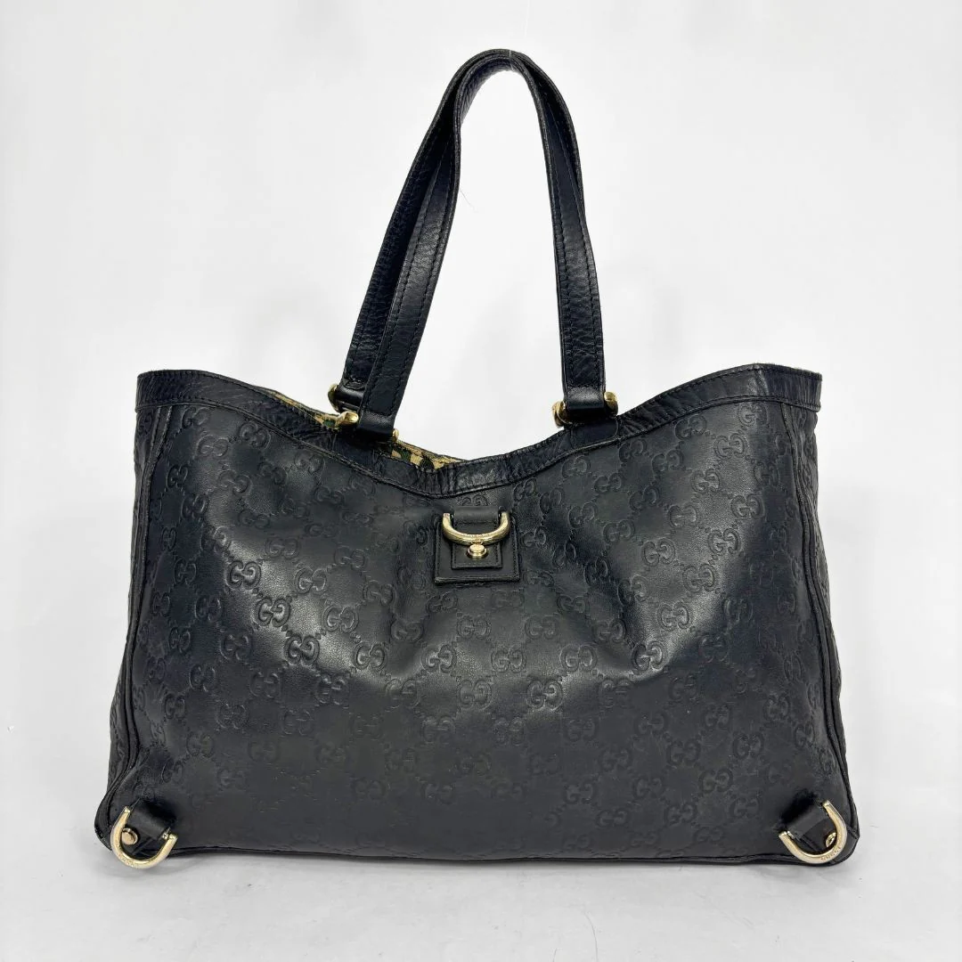 Black leather handbag with gold hardware on a white background