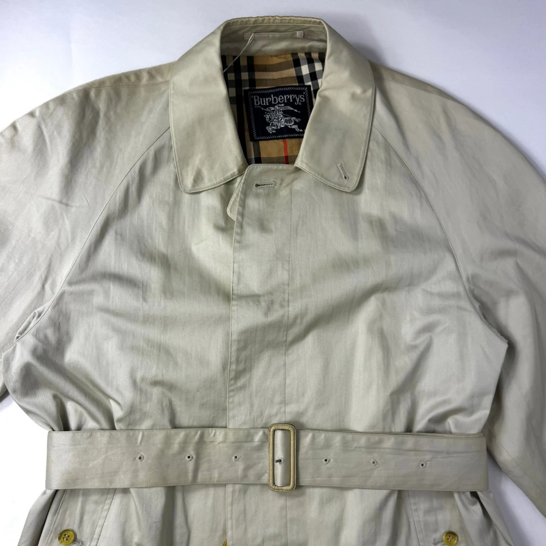 Beige trench coat worn by a person on a white background