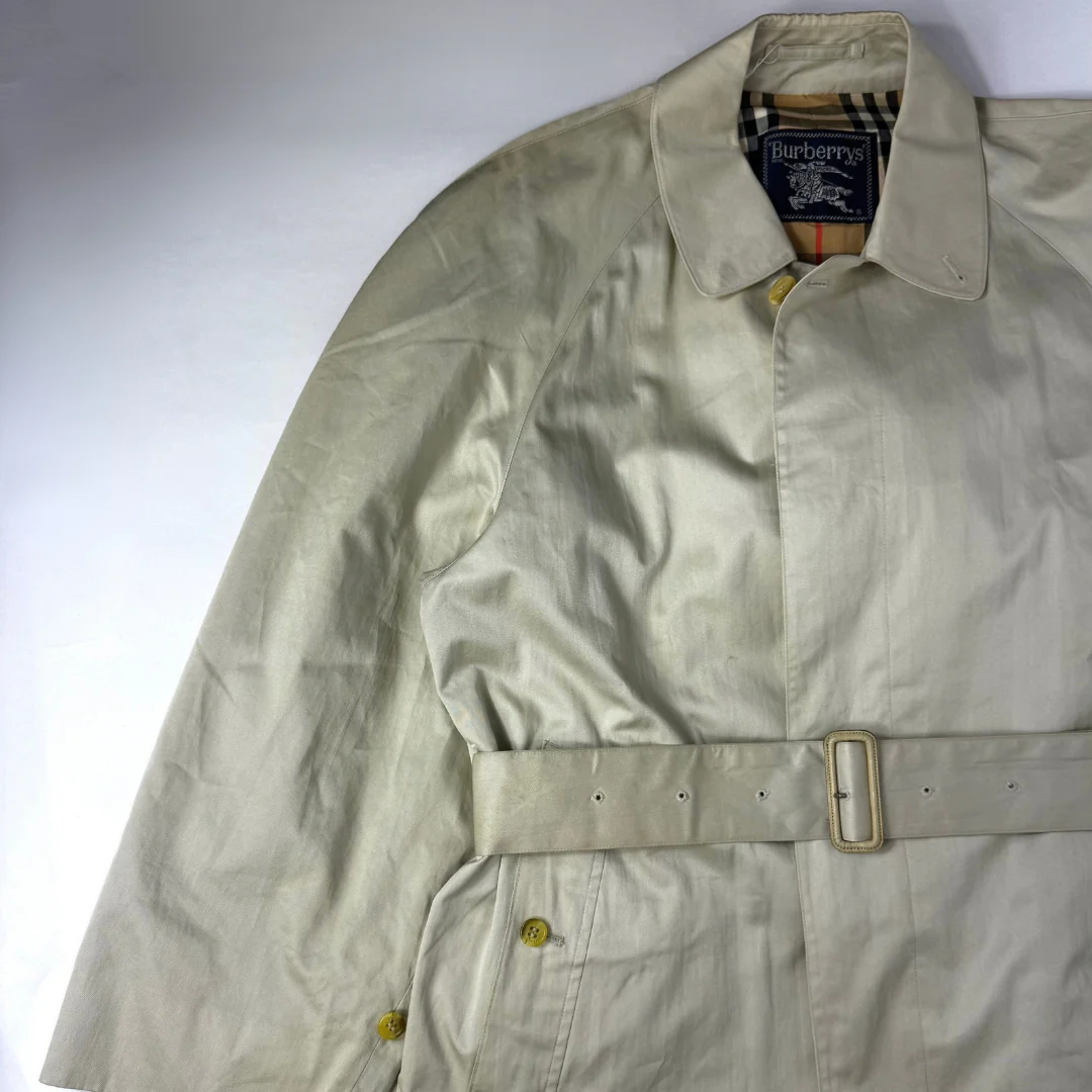 Beige trench coat worn by a person on a white background