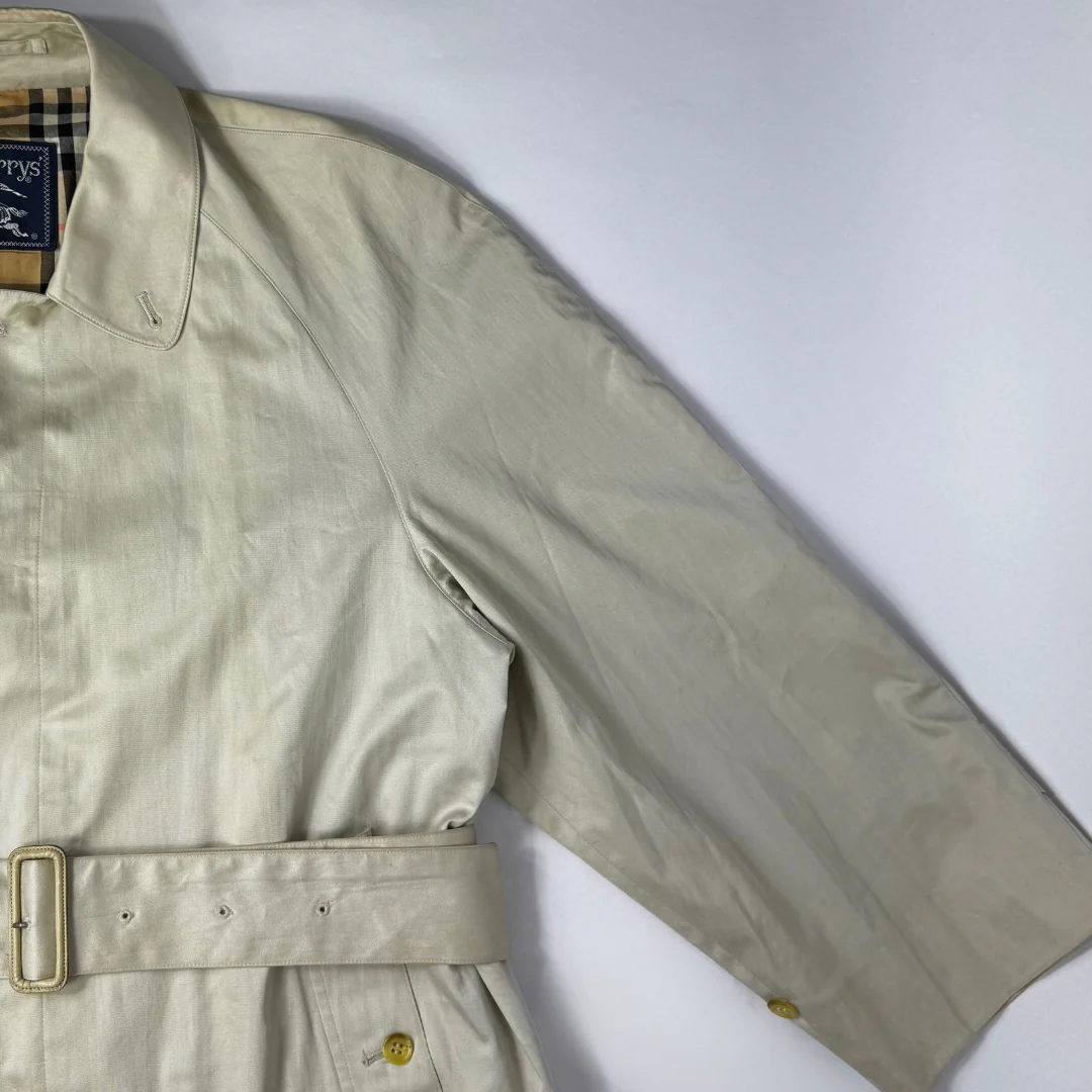 Beige trench coat worn by a person on a white background