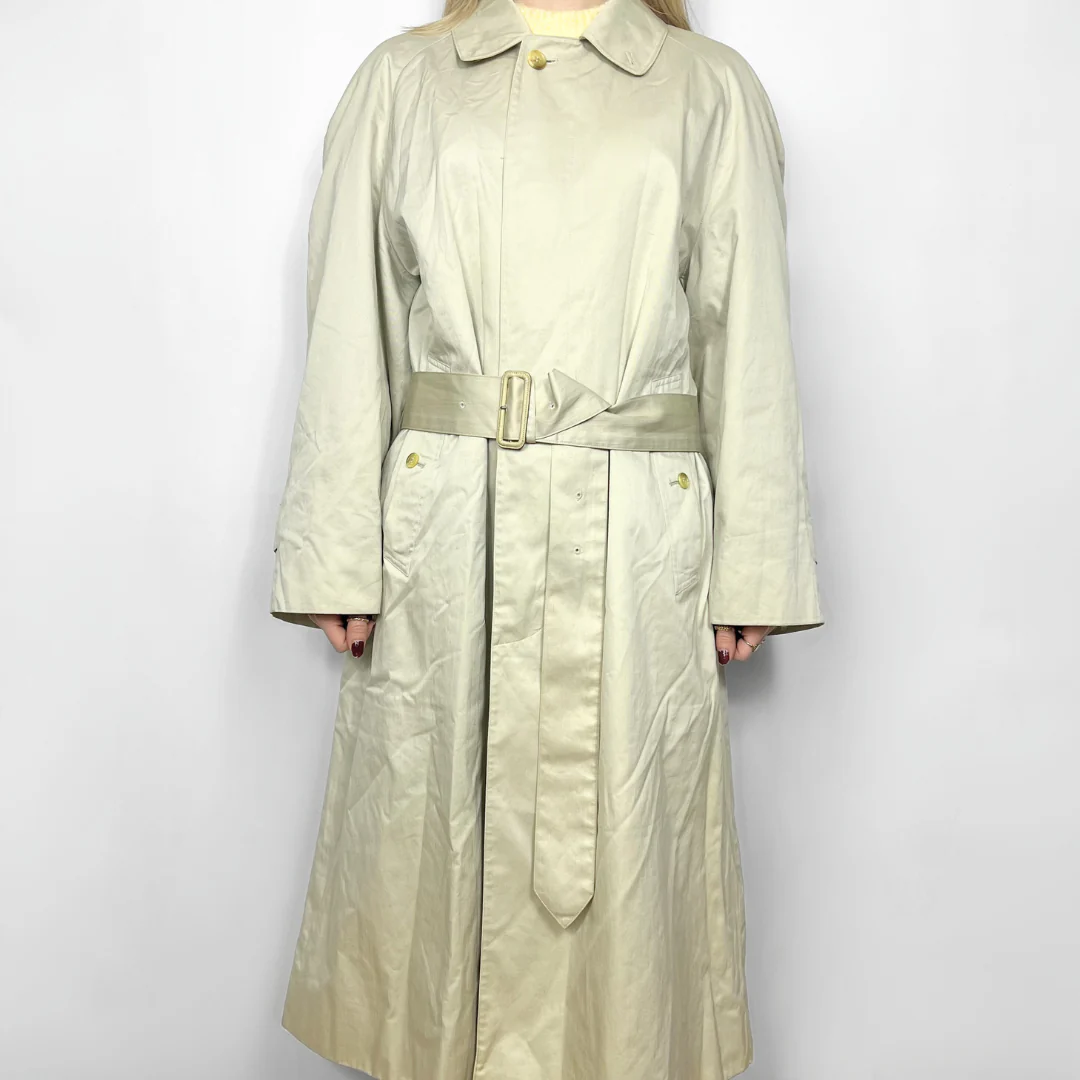 Beige trench coat worn by a person on a white background