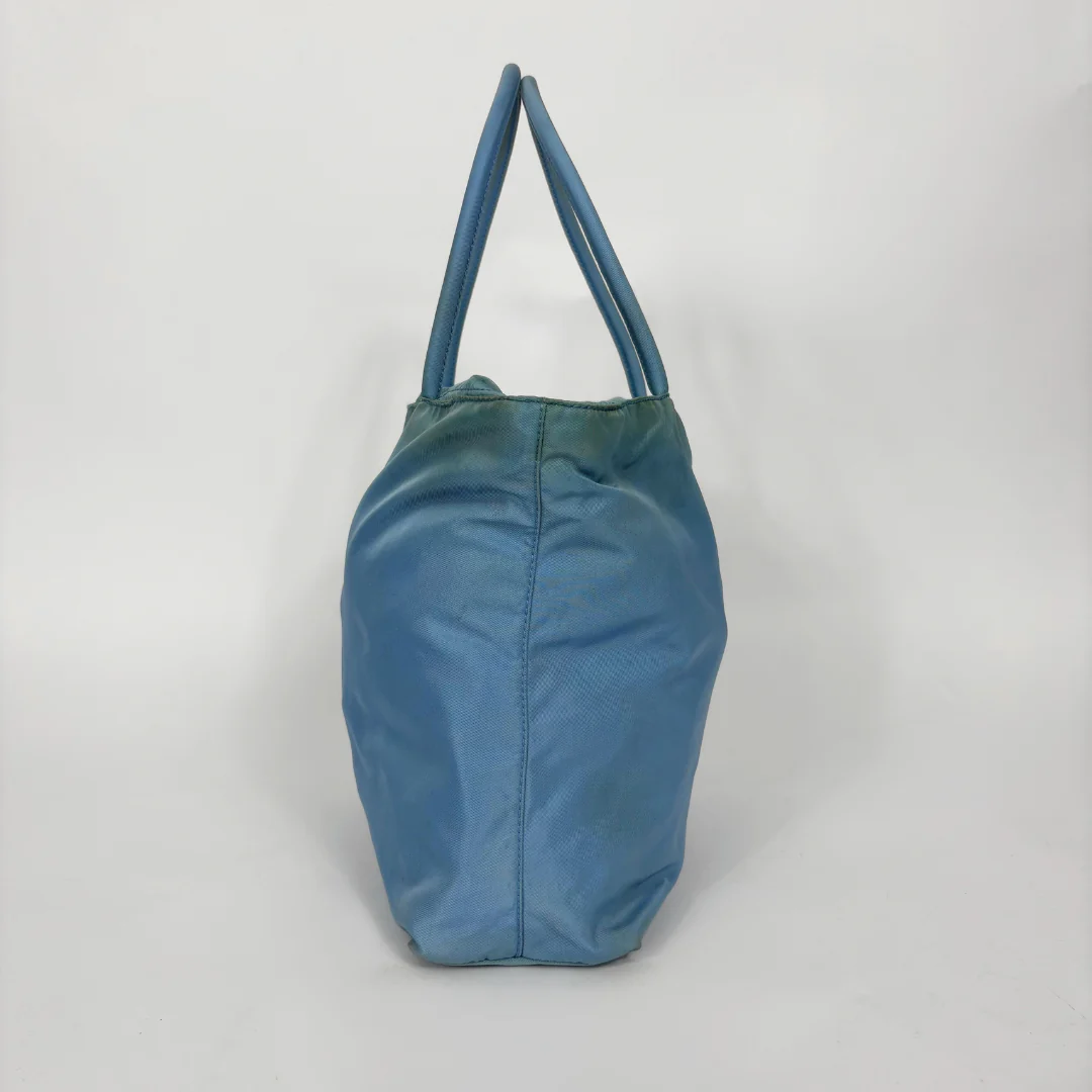 Prada light blue nylon tote bag with matching top handles and the signature enamel triangle logo.