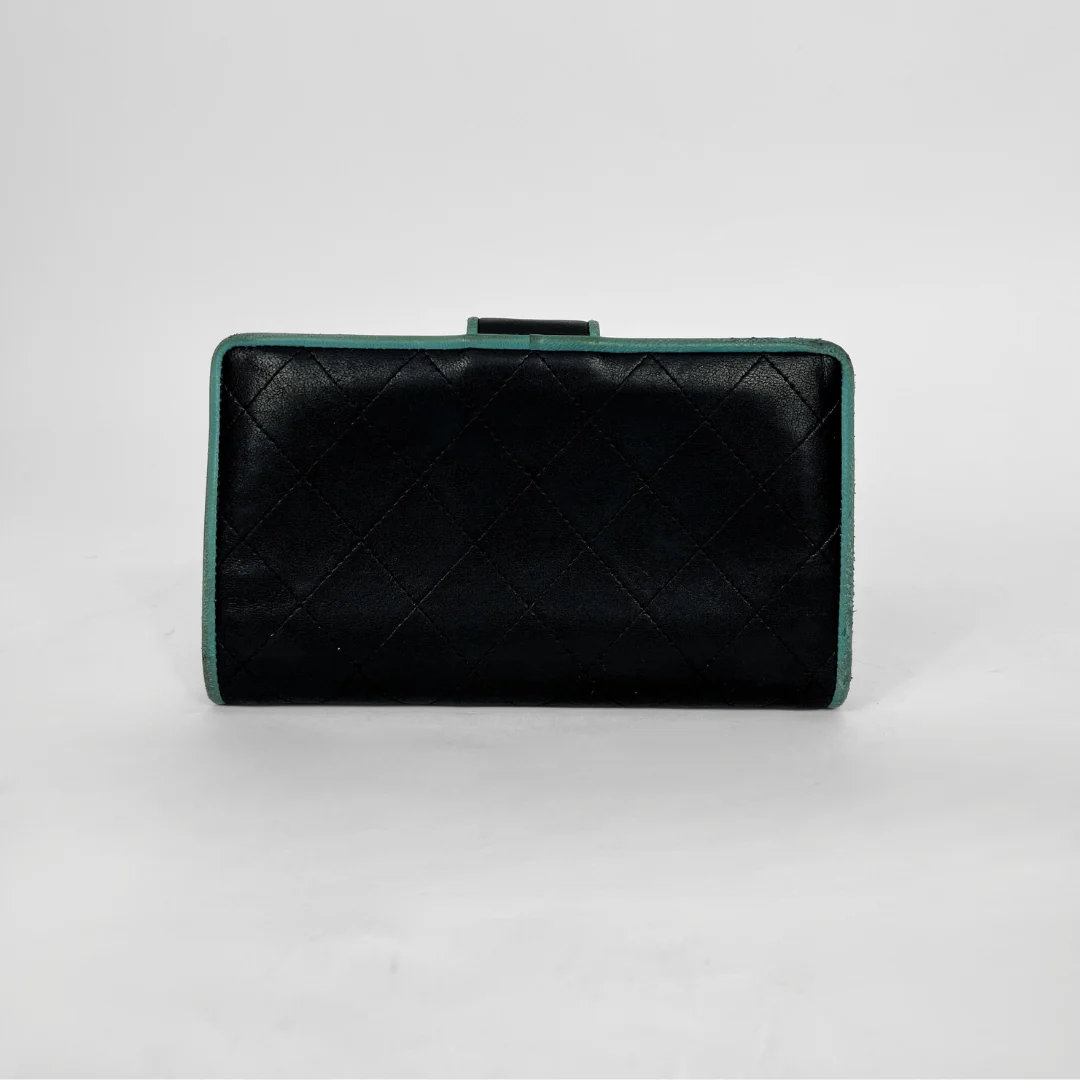 A black quilted leather clutch bag with a mint green trim, photographed against a neutral light gray background.