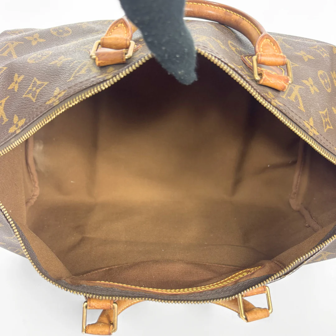 Open brown leather handbag with gold monogram pattern on a white background