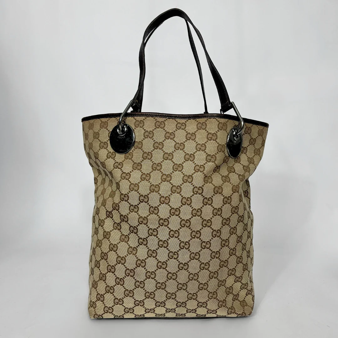 Beige handbag with black handles and trim on a white background