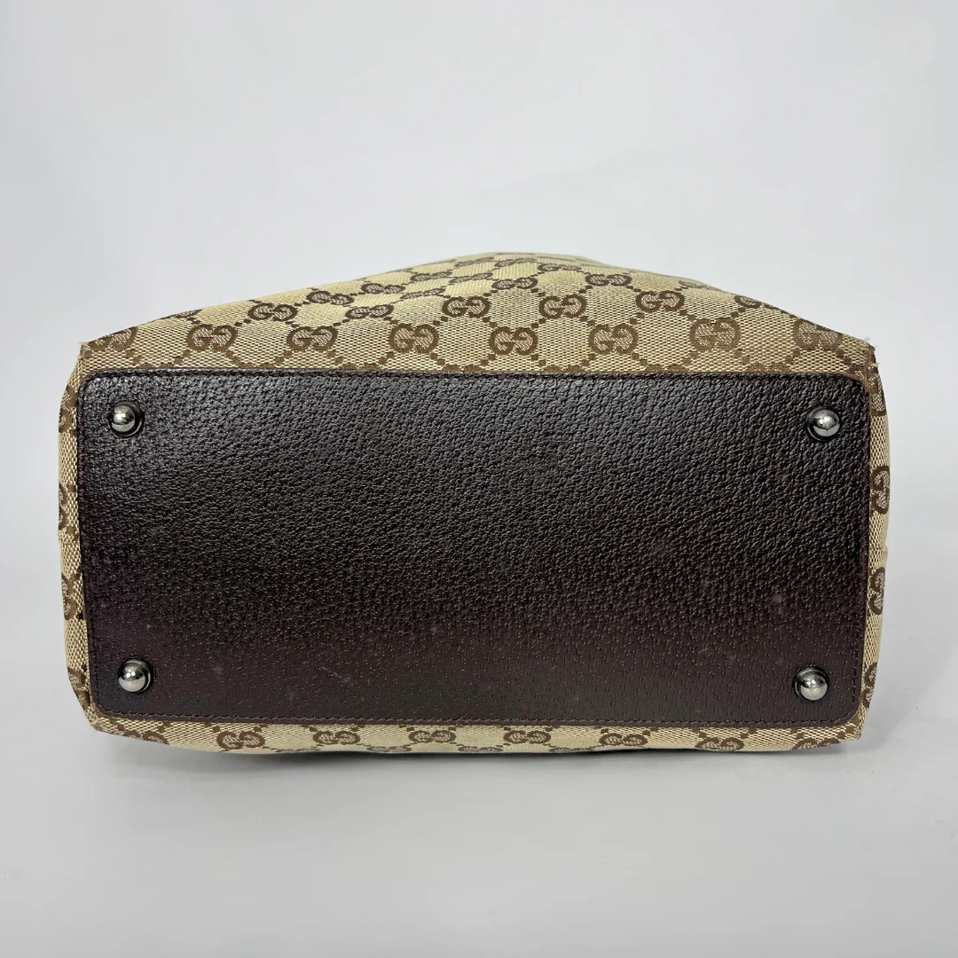 Designer handbag with patterned top and dark brown base on a light gray background