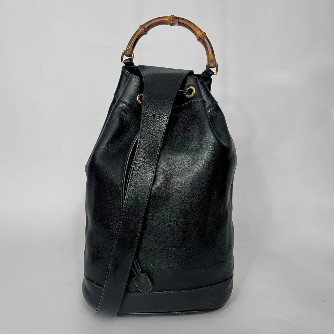 Black leather backpack with bamboo handle on a gray background