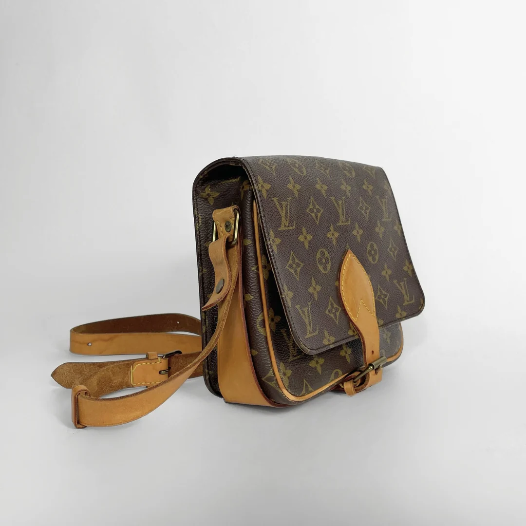 A Louis Vuitton monogram canvas shoulder bag with tan leather trim and strap, shown on a light gray background.