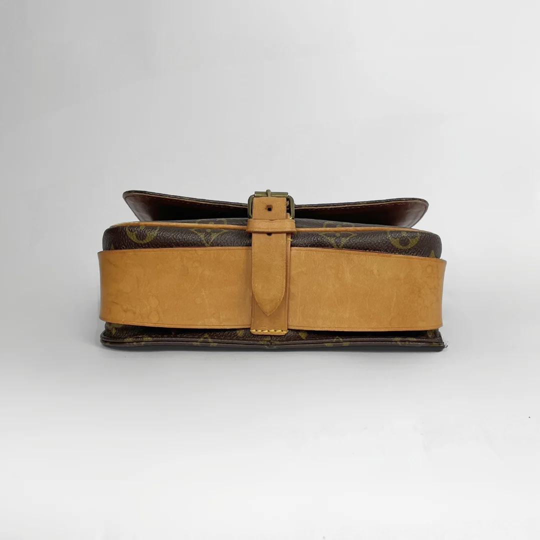 A vintage Louis Vuitton shoulder bag in brown monogram canvas with a wide tan leather strap and a matching tan leather buckle strap, photographed against a light gray background.