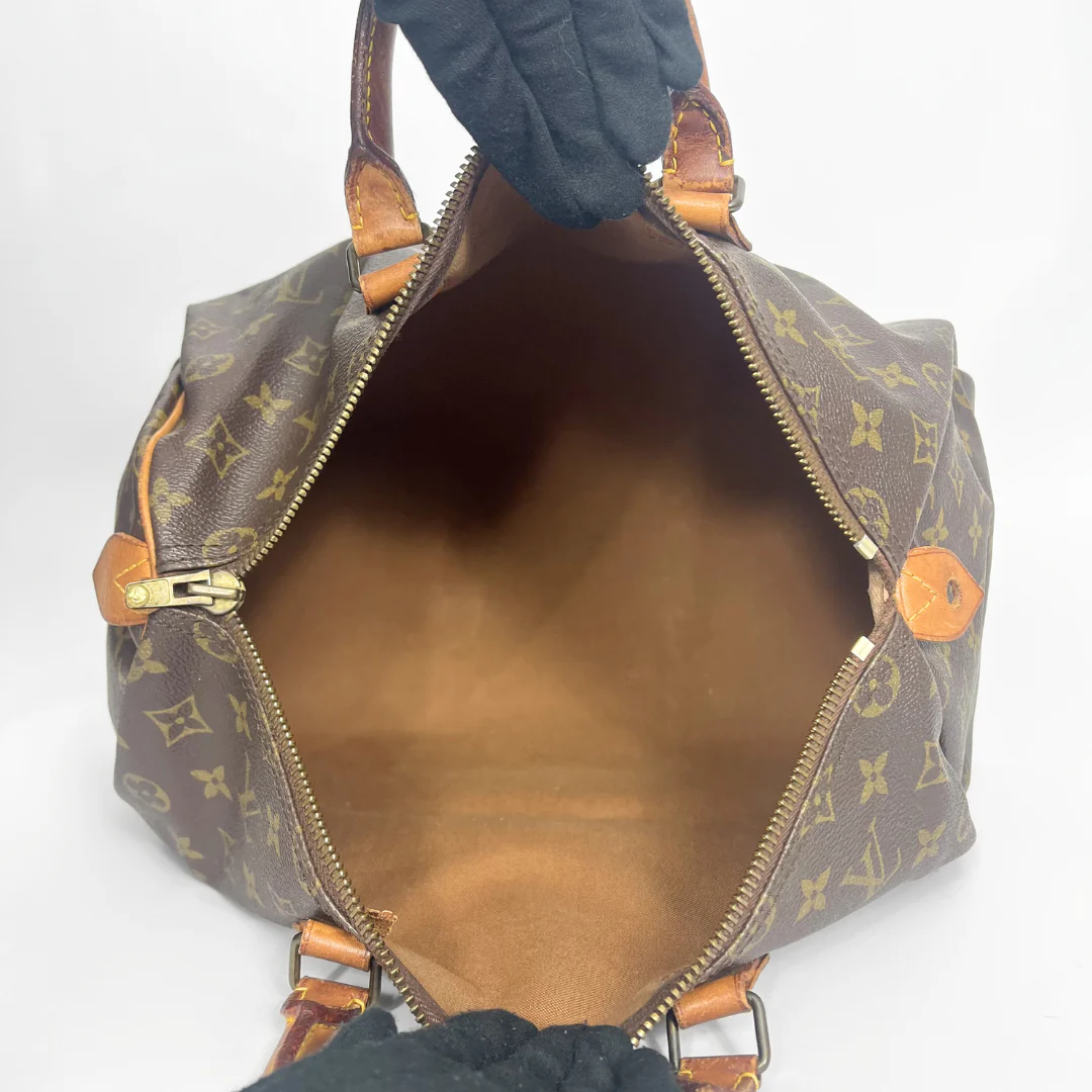 Brown monogram handbag with gold accents on a white background