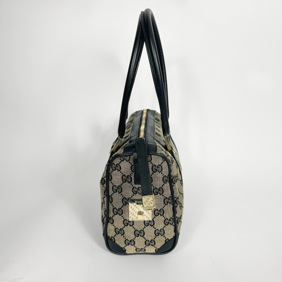 Designer handbag with black handles and trim on a light gray background