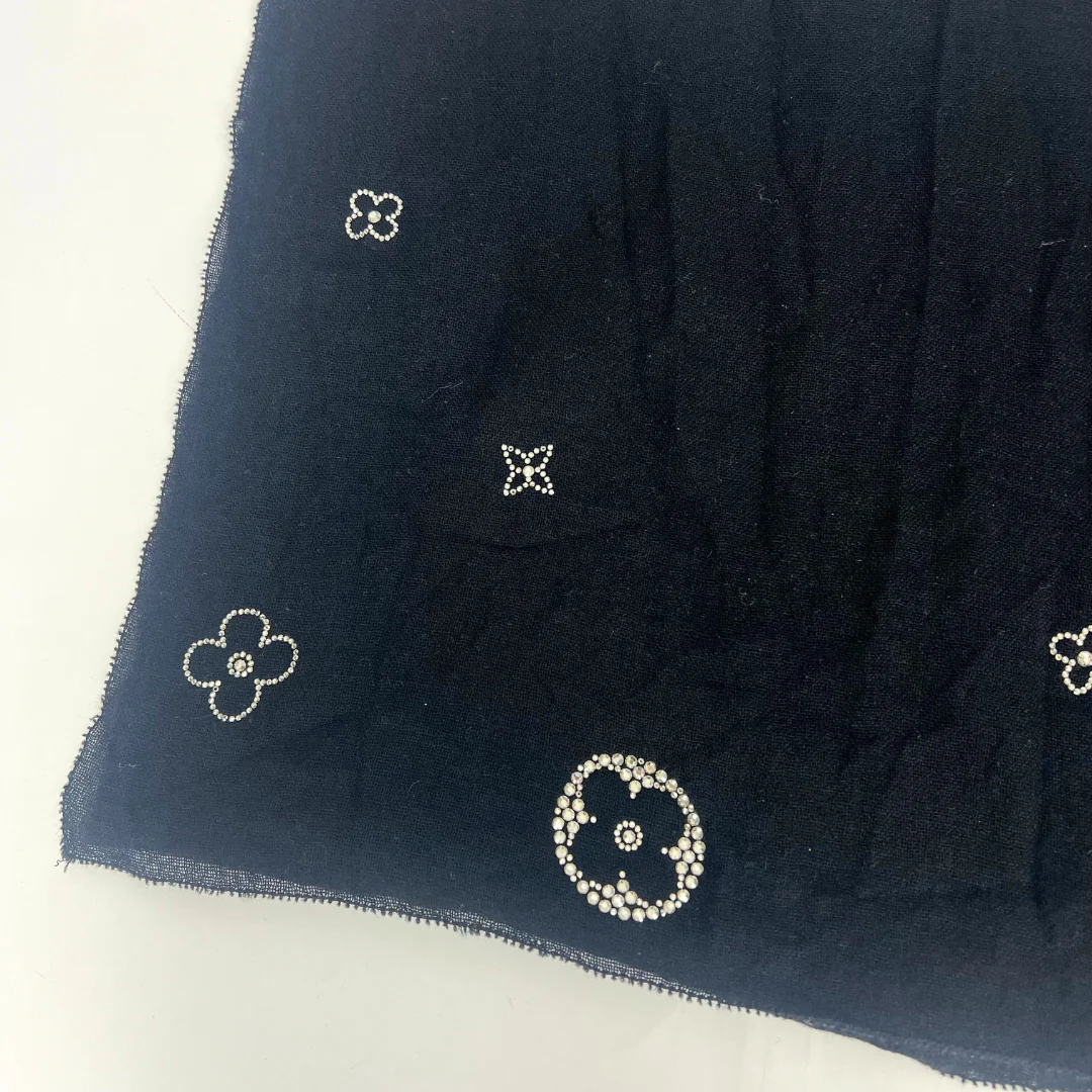 Black fabric with floral bead embellishments on a light background
