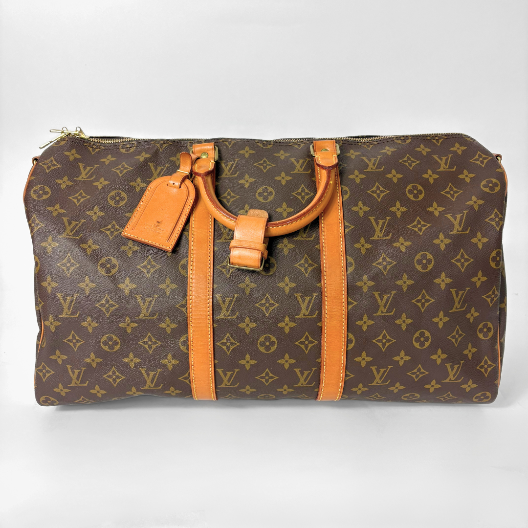 Brown monogram patterned bag with tan leather handles and trim on a white background