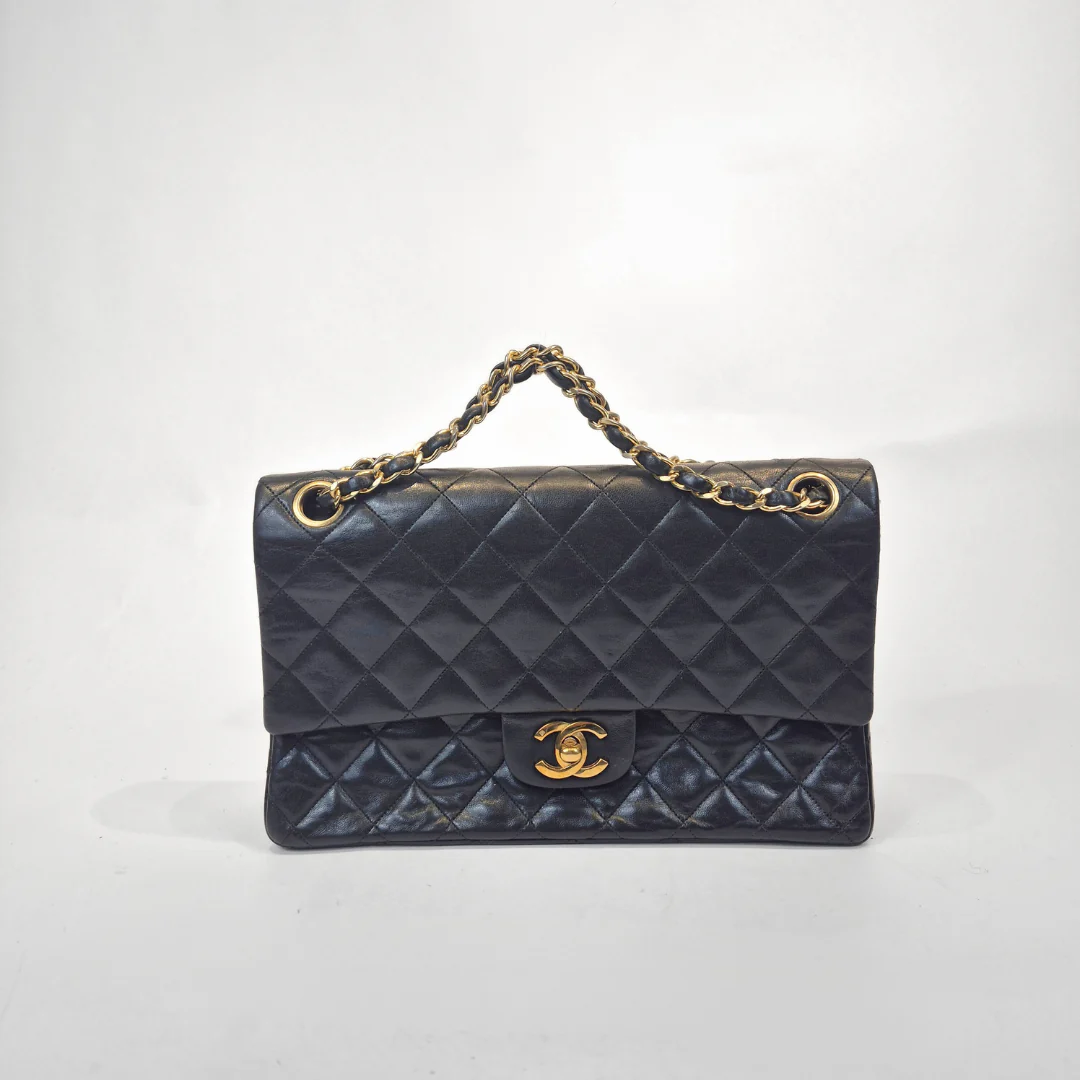 Black quilted handbag with gold chain handle and clasp on a white background