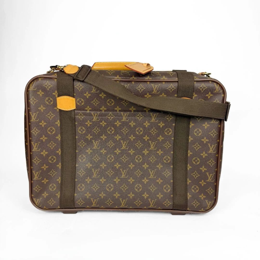 Brown suitcase with monogram pattern and yellow accents on a white background