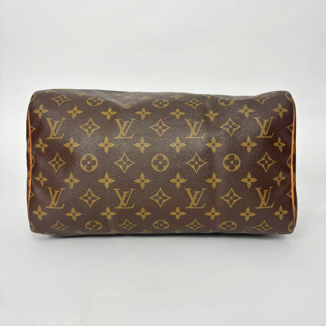 Brown leather handbag with gold monogram pattern on a white background