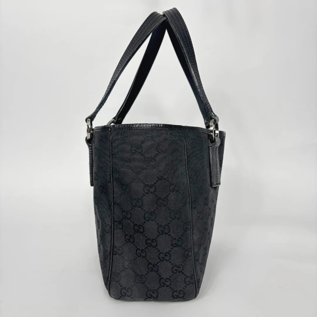 Black textured handbag with brand logo on a light gray background
