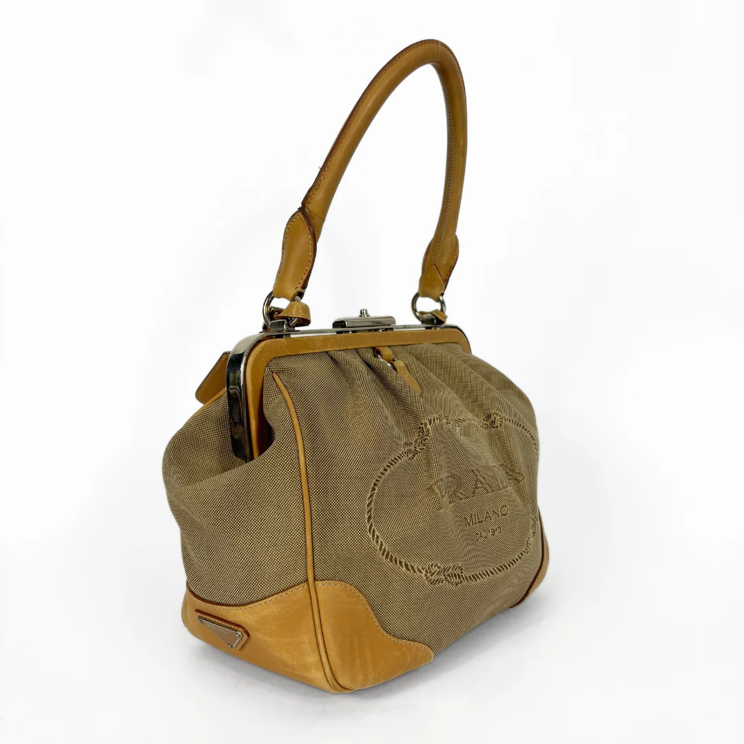 Brown handbag with tan leather accents on a white background