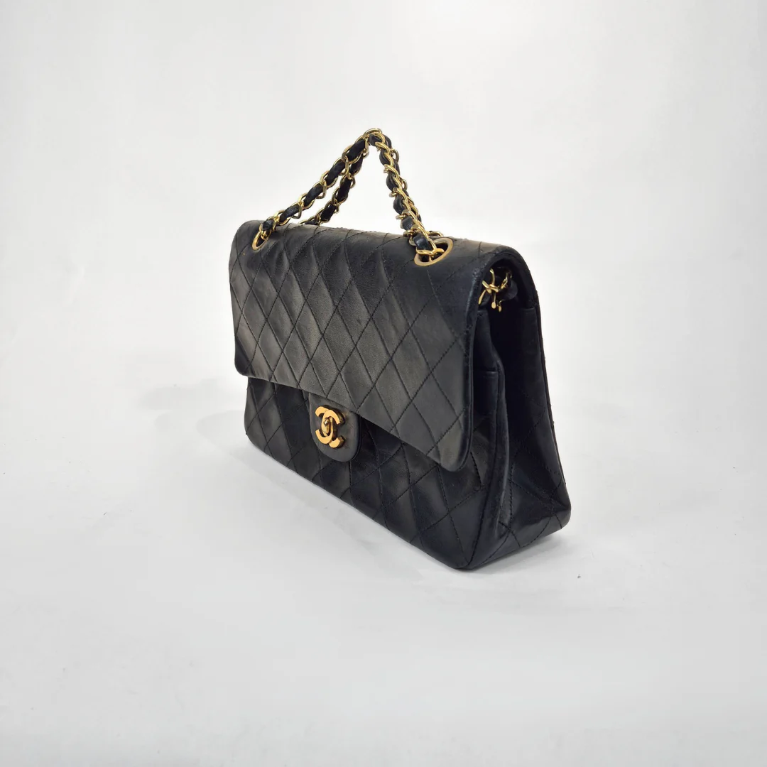 Black quilted handbag with gold hardware on a white background