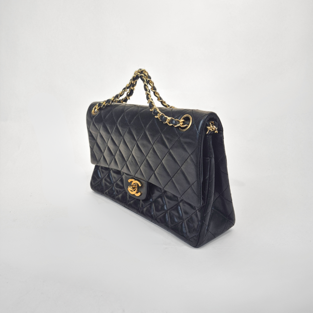 Black Chanel handbag with gold chain handle and clasp on a white background