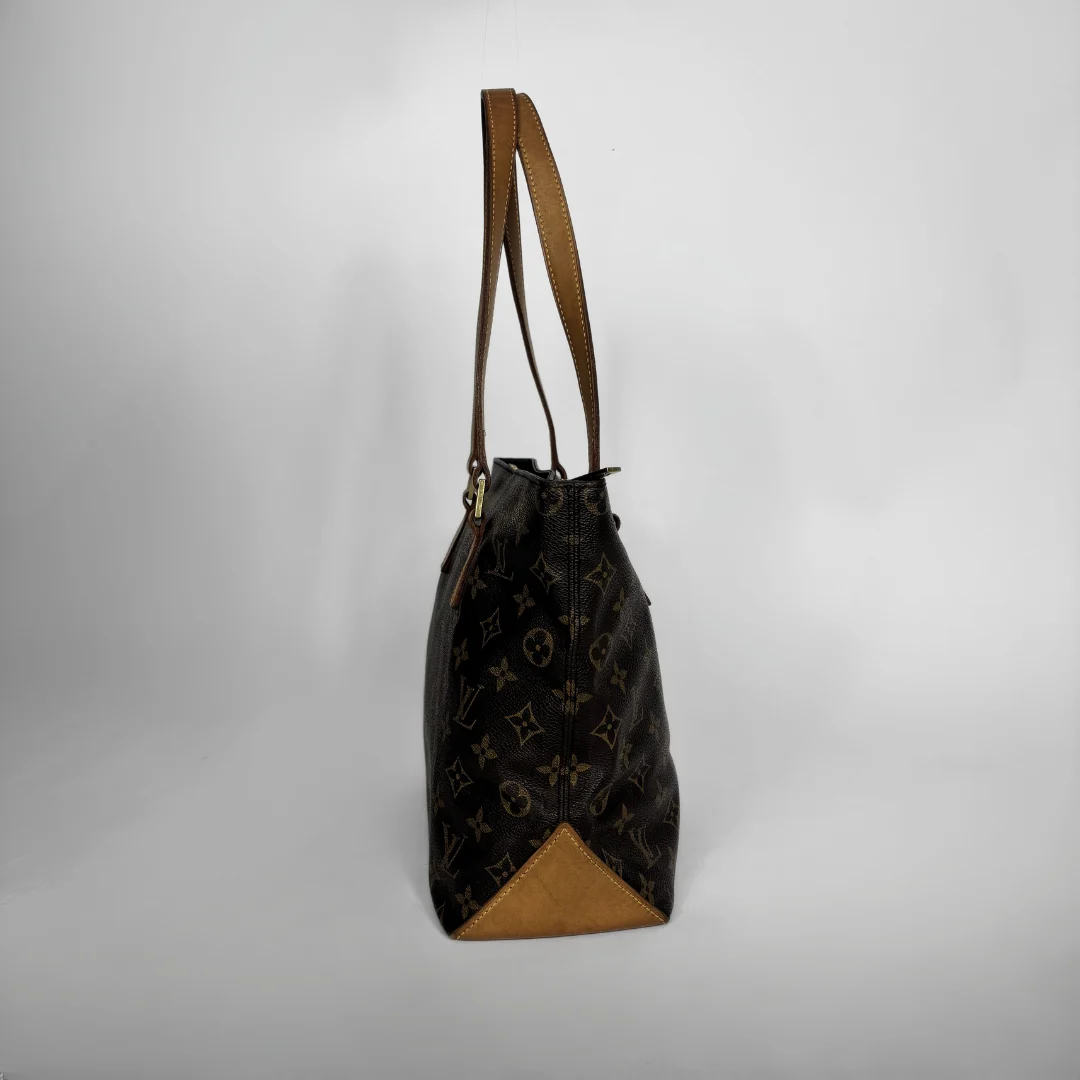 A Louis Vuitton monogram canvas shoulder bag with brown leather trim and a triangular tan leather base, shown against a plain light gray background.