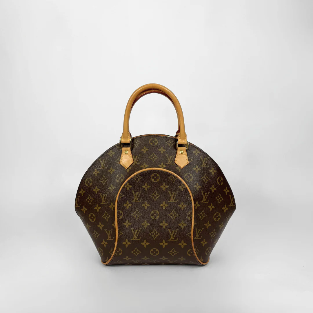 Brown handbag with gold accents held by a gloved hand on a white background