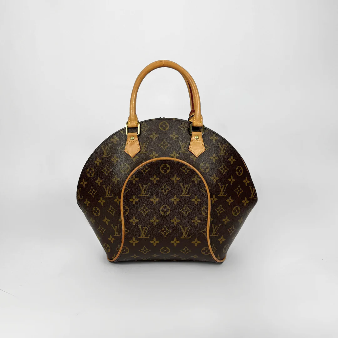 Brown handbag with gold accents held by a gloved hand on a white background