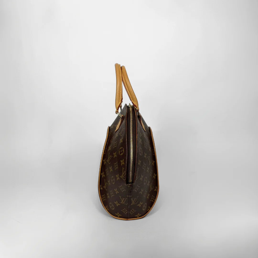 Brown handbag with gold accents held by a gloved hand on a white background