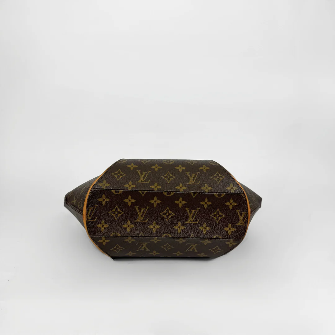 Brown handbag with gold accents held by a gloved hand on a white background