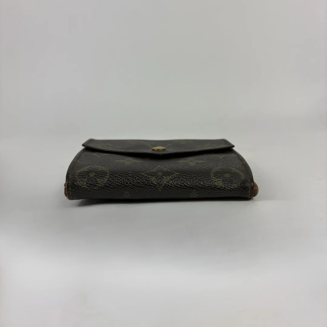 A Louis Vuitton monogram canvas wallet in dark brown with gold-tone hardware, photographed against a neutral light gray background.