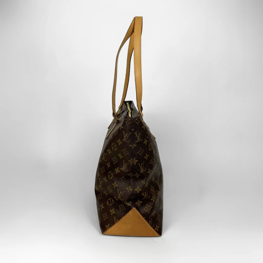 Brown monogram handbag with tan leather handle on a white background