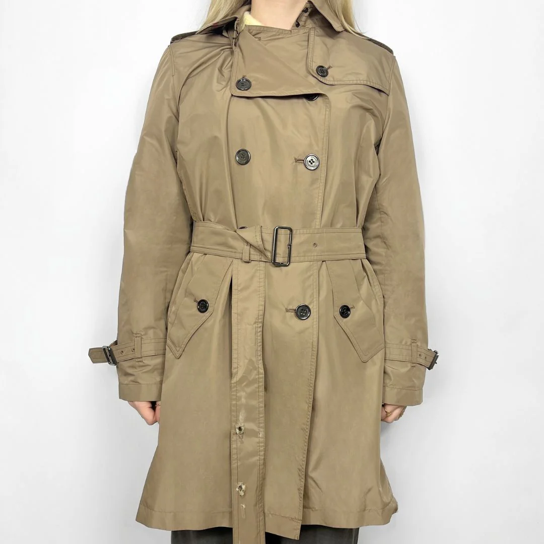 Beige trench coat worn by a person on a white background