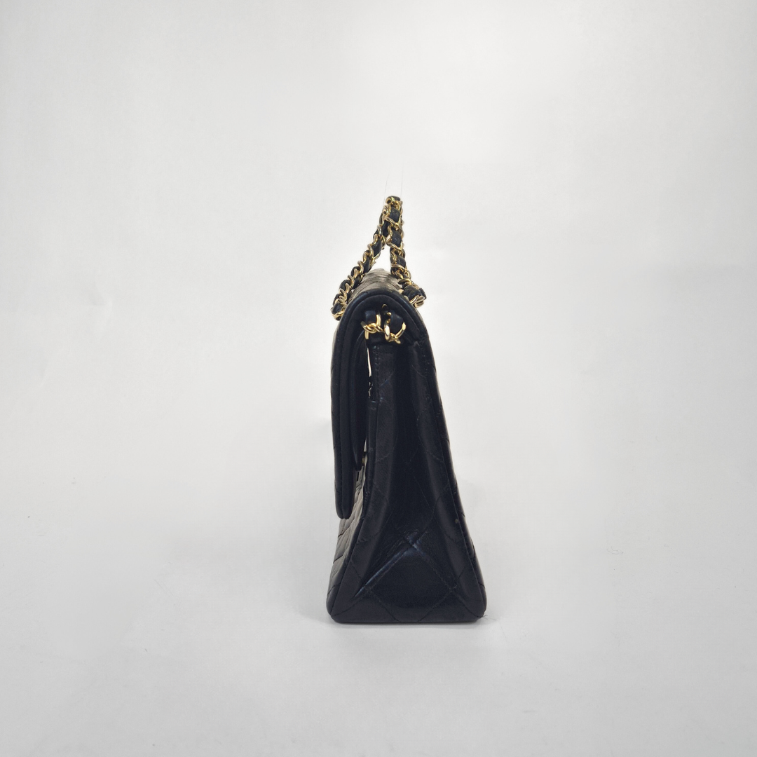 Black Chanel handbag with gold chain handle and clasp on a white background