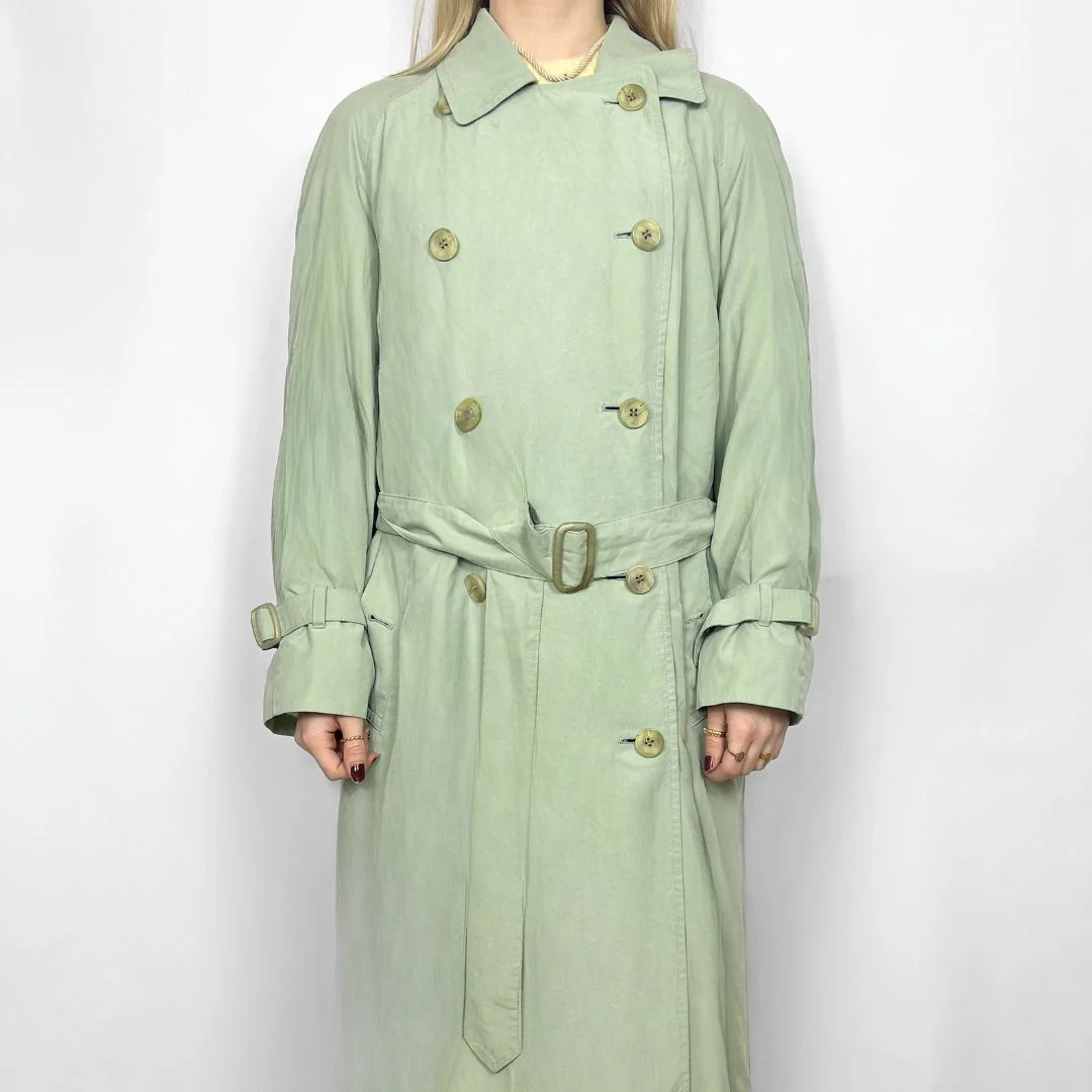 Light green trench coat with gold buttons on a white background