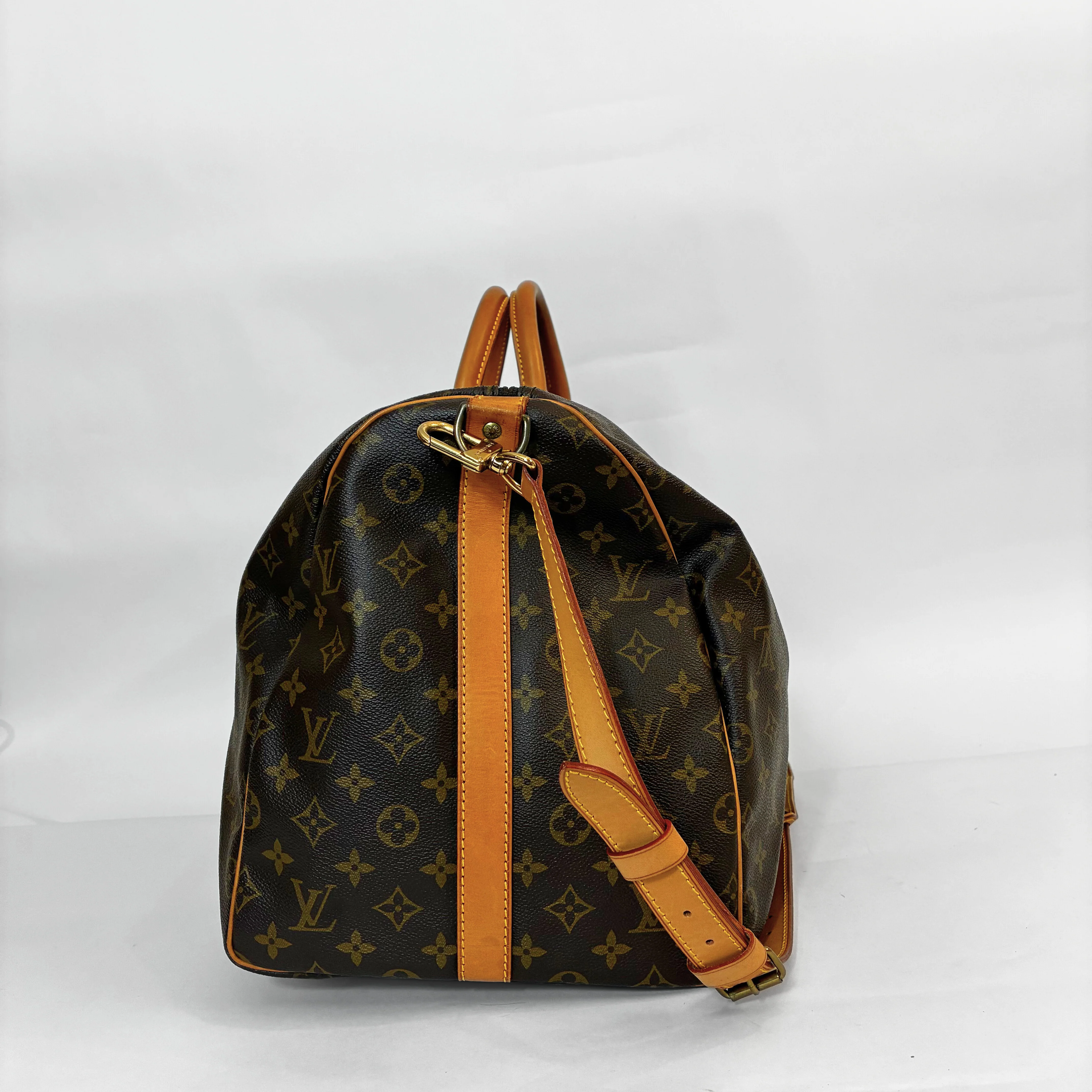 Louis Vuitton monogram travel bag with brown leather straps on a white background