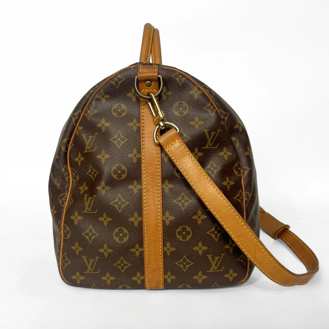 Brown leather handbag with gold monogram pattern on a white background