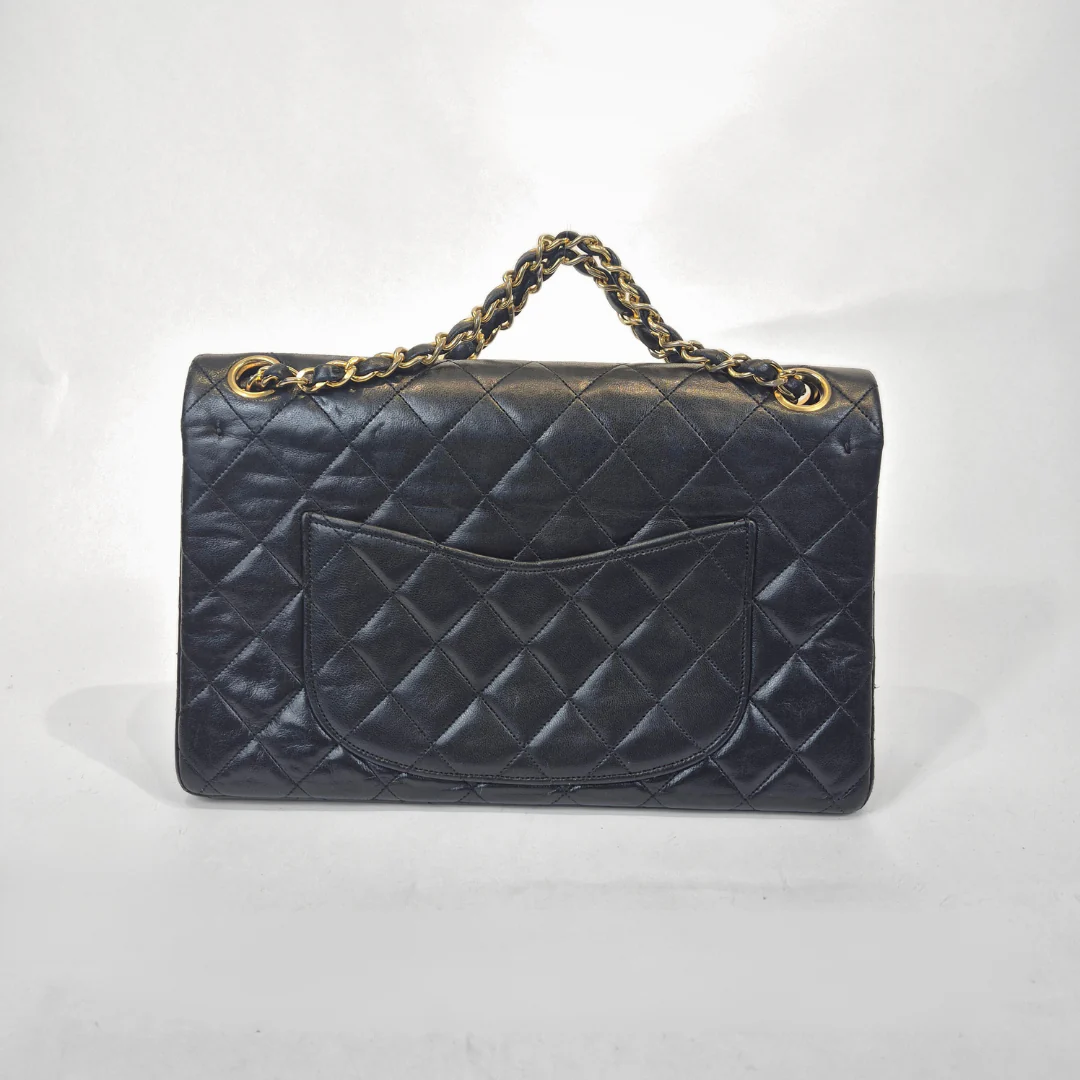 Black quilted handbag with gold chain handle on a white background