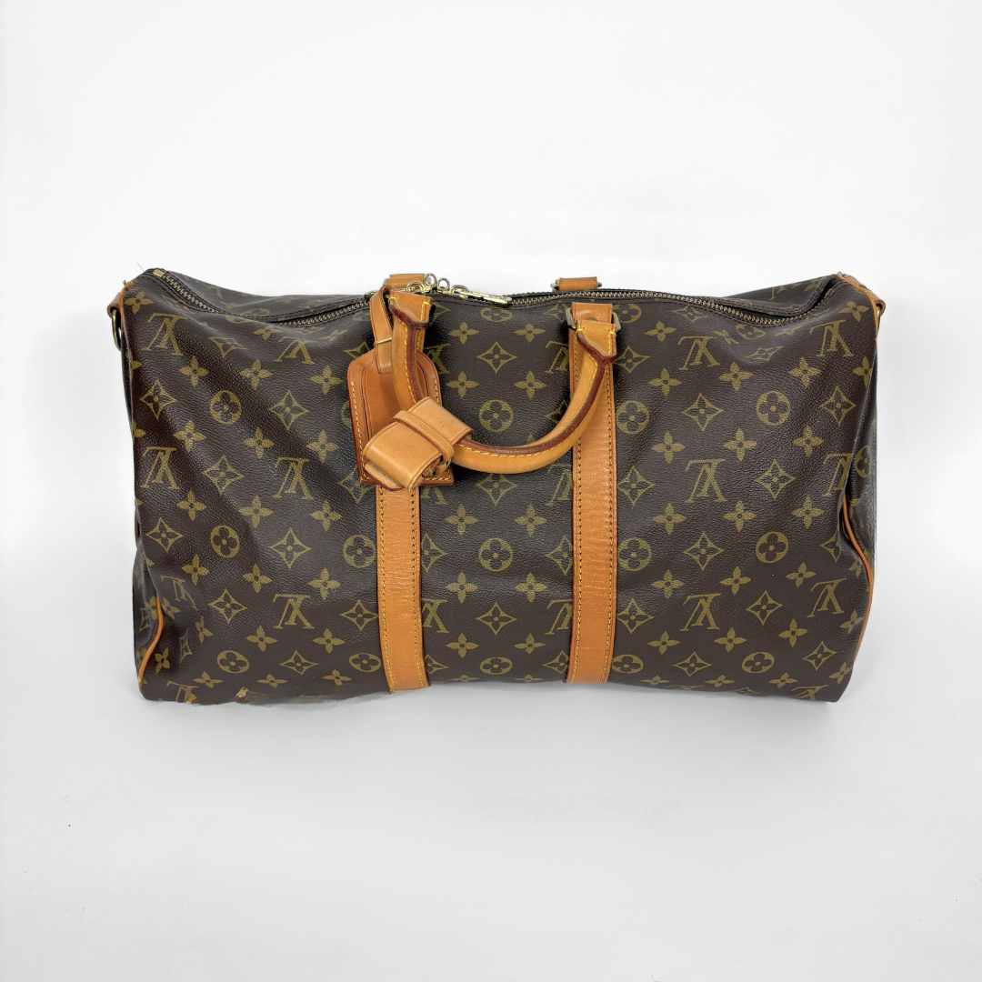 Brown monogram duffel bag with tan leather handles and straps on a white background