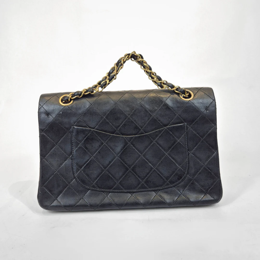 Black quilted handbag with gold chain handle on a white background