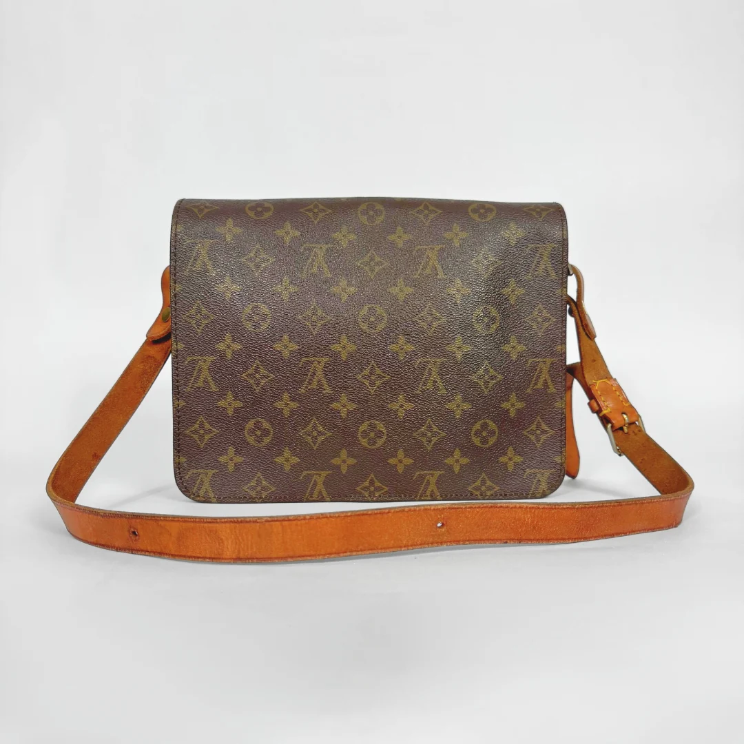 Brown monogram handbag with tan leather strap on a white background